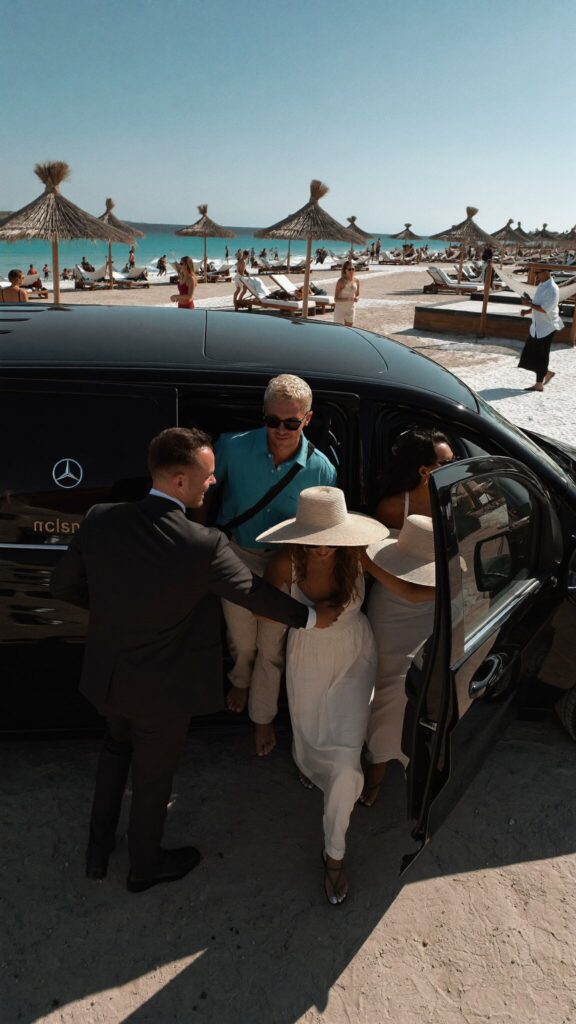 Chauffeur helping guests into a Mercedes-Benz V-Class at a beach club